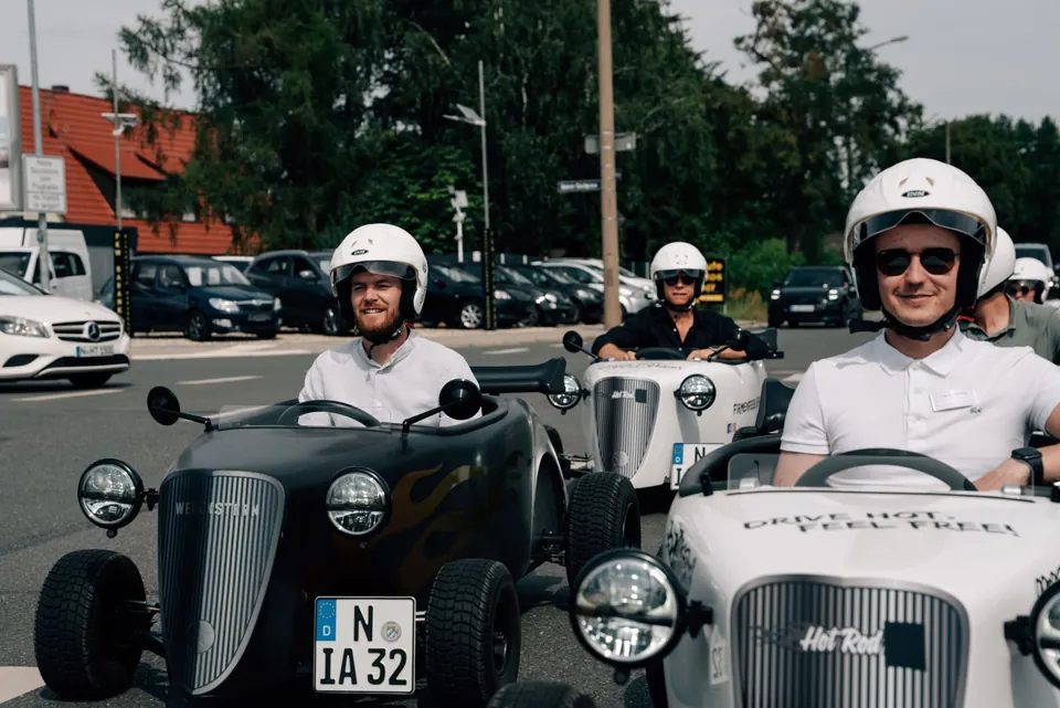 Lächelnde Fahrer in weißen und schwarzen Hot Rods vor dem Start